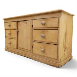 Victorian stripped pine sideboard, rectangular plank top rounded edges, with central cupboard door with shaped panel, flanked by two banks of three graduating drawers with turned knobs, raised on a plinth base 