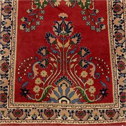 Kashan design wool runner, red field decorated with repeating floral medallions, palmettes and scrolling foliate motifs, enclosed by cream floral border and fringed ends