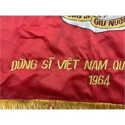 1960s North Vietnam banner embroidered in yellow thread on a red ground, roughly translates as 'Peoples Army of Viet Nam. Warriors of Viet Nam Determined To Keep The Country 1964' around a central military crest with the motto 'Warriors Keep The Country'; tassels to three sides 70 x 100cm