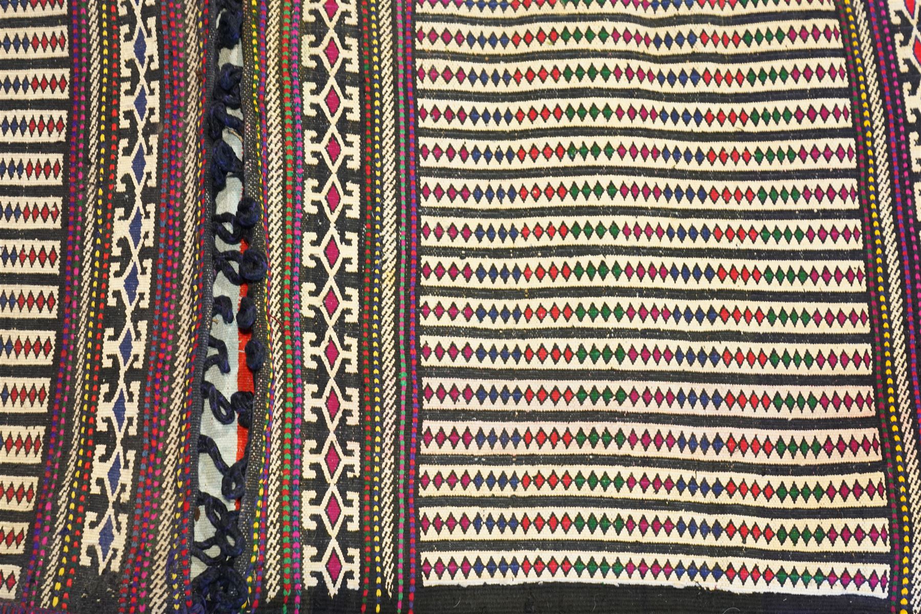 North East Persian Turkoman saddle bag, traditional double pouch form, each panel woven with vertical bands of small geometric motifs on ivory ground, framed by multiple horizontal borders of angular tribal ornament of hooked devices and steeped lozenges, reverse with stripped coloured flatweave bands 