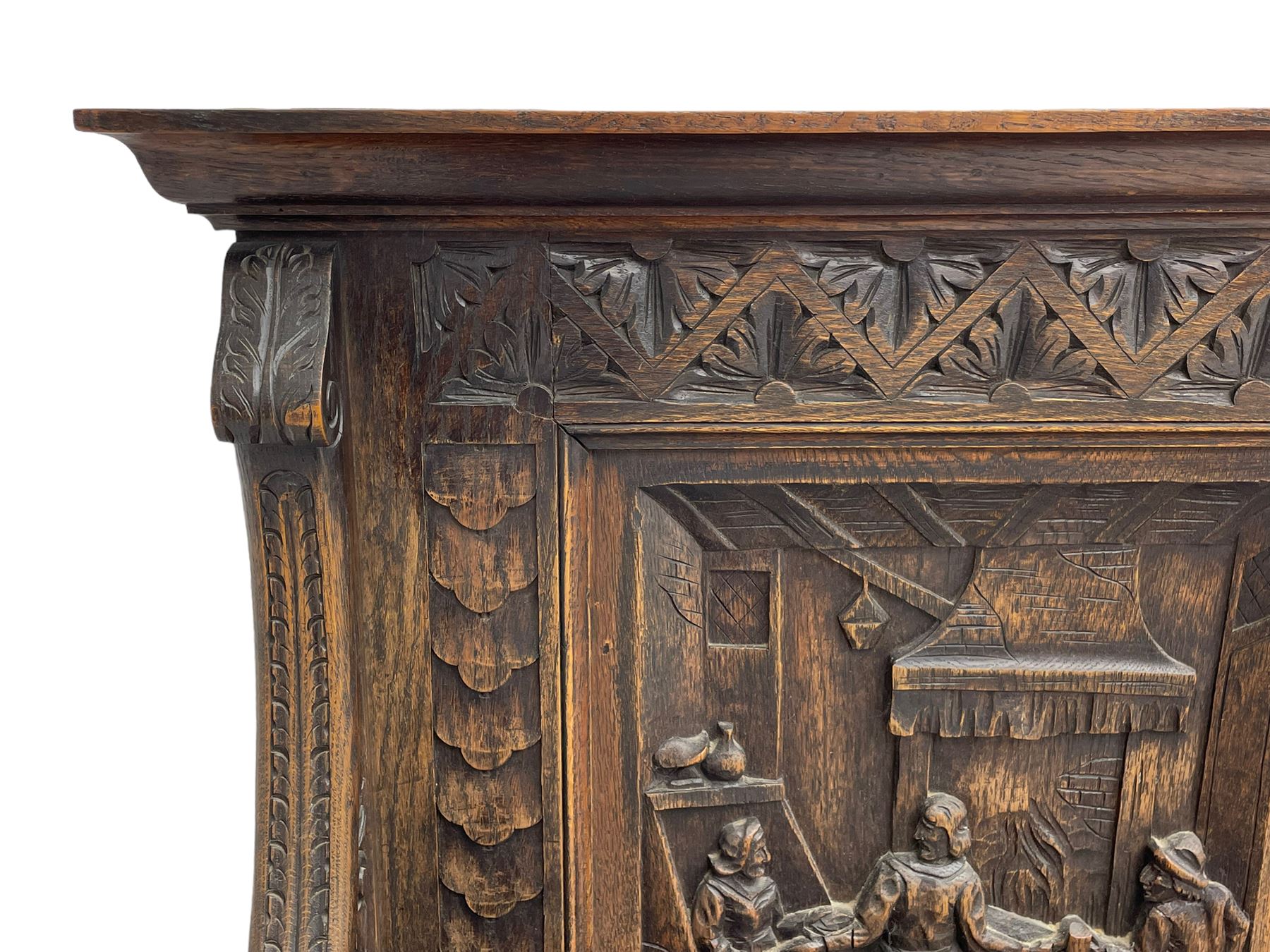 19th century heavily carved oak settle, the moulded upper rail over triangular foliage carved frieze, three Flemish style carved panels depicting tavern scenes, acanthus carved uprights terminating to lion carved arms, hinged box seat, the panelled front carved with lion masks and extending scrolled acanthus leaves, on moulded skirt base