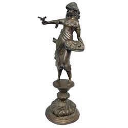 Bronzed figure of a woman, with bird perched upon her outstretched arm, upon a circular raised plinth, H47 
