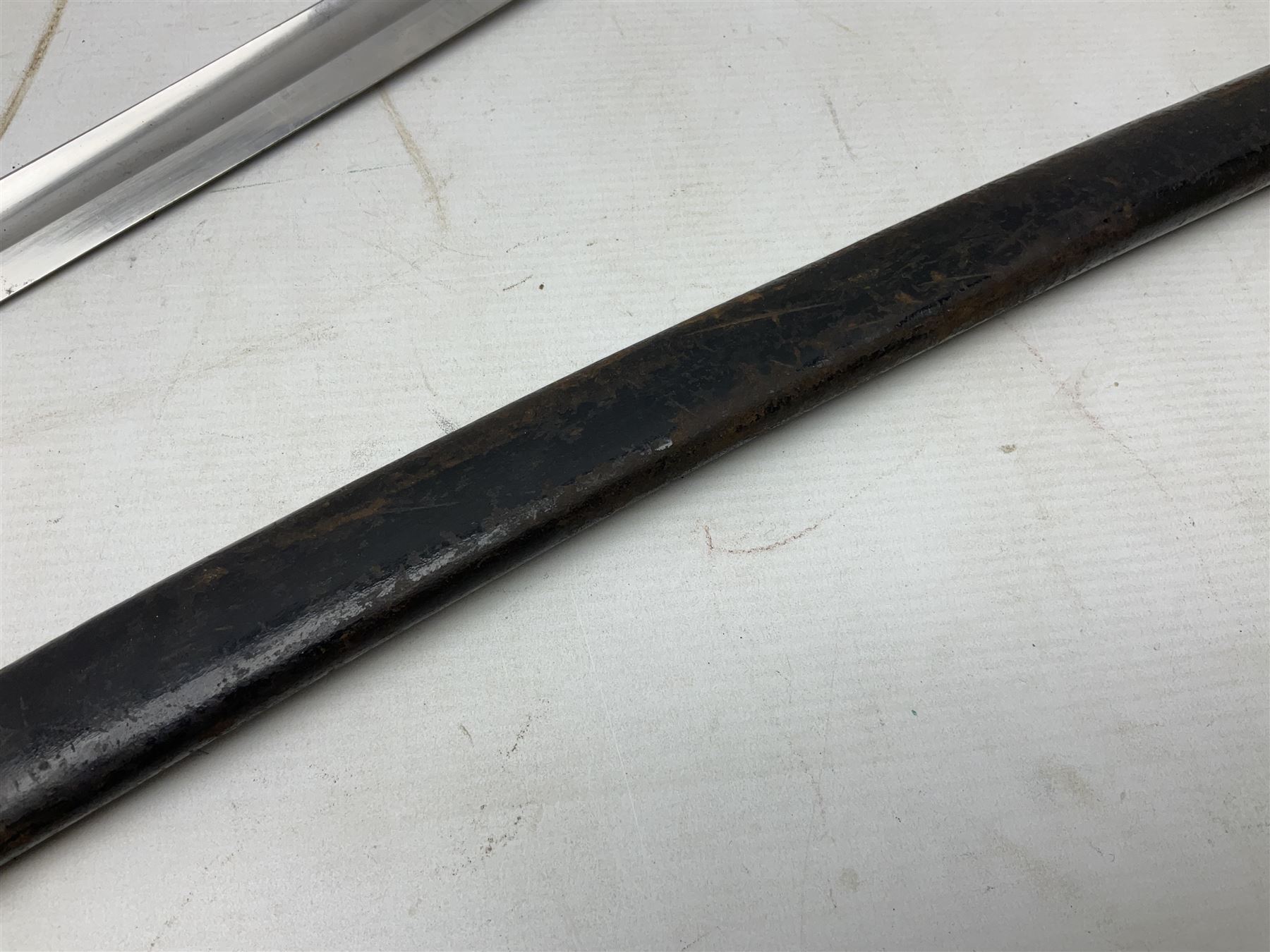 Mid-19th century Custom’s officer/Constabulary sidearm, with plain 60.5cm slightly curving fullered blade double edged at tip,  steel knucklebow and downswept quillon, stepped pommel and ribbed fishskin grip; in leather covered scabbard with steel locket, frog stud and chape L76cm overall