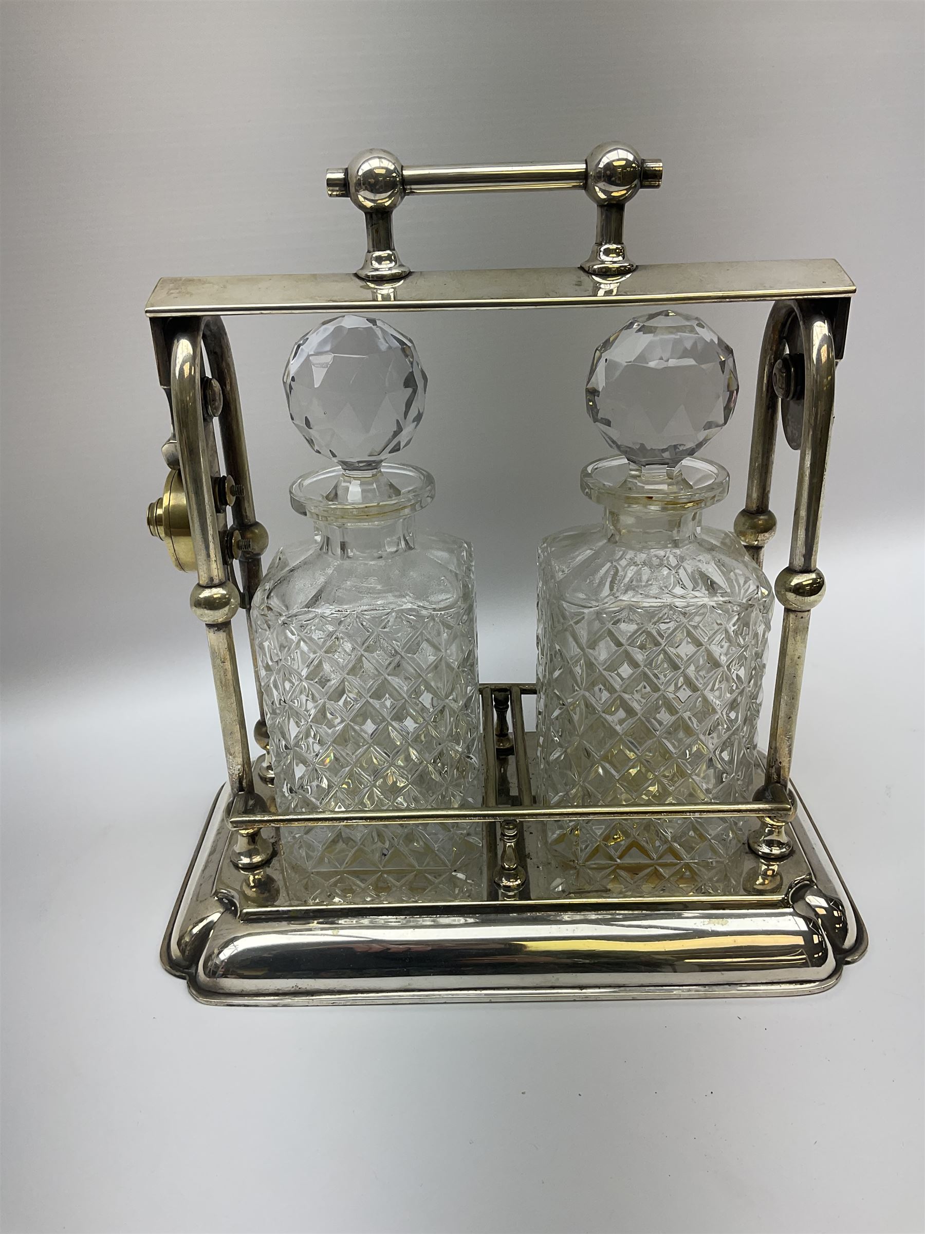Early 20th century silver plated tantalus by John Grinsell & Sons of Birmingham, containing two crystal glass decanters, with key, H31cm