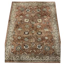 Persian design carpet, rust ground field decorated with large stylised plant motifs surrounded by smaller floral motifs, repeating trailing border