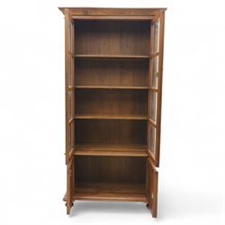 Pair of late 20th century Thai hardwood display cabinets, each with moulded cornice over twin glazed doors enclosing adjustable shelves, panelled cupboard doors below flanked by fluted columns, raised on bun feet