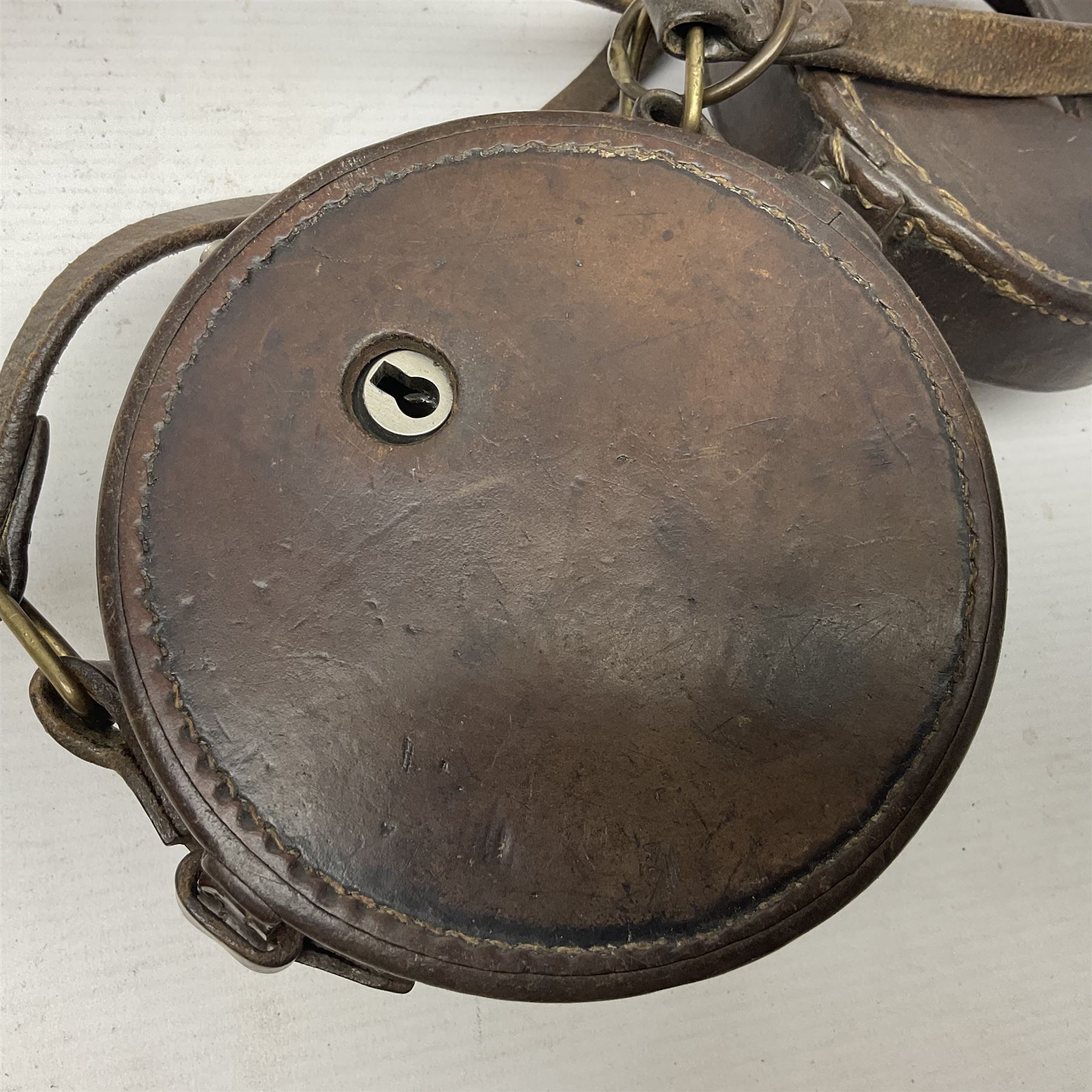 Metal cased drum shaped travelling clock with grey hammered finish, French clockwork movement and stitched leather outer case with shoulder strap; bears manuscript label 'Royal Armament Research and Development Establishment - serial no.09433' D13cm overall