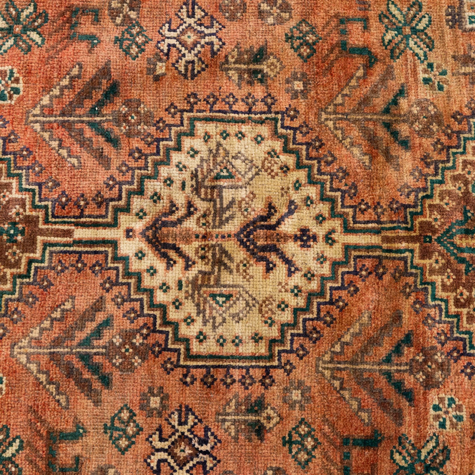 South West Persian Qashqai hand-knotted rug, salmon pink field with central stepped geometric medallion with issuing stylized tree and floral motifs, surrounded by angular devices, with indigo spandrels and multiple geometric borders, fringe ends 