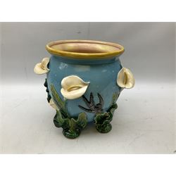 George Jones style majolica jardiniere of globular form, supported on four feet formed from modelled lily leaves growing up the side of the pot, with swallows flying amongst the white lily flowers, all set against a blue ground, with a pink interior, H27cm