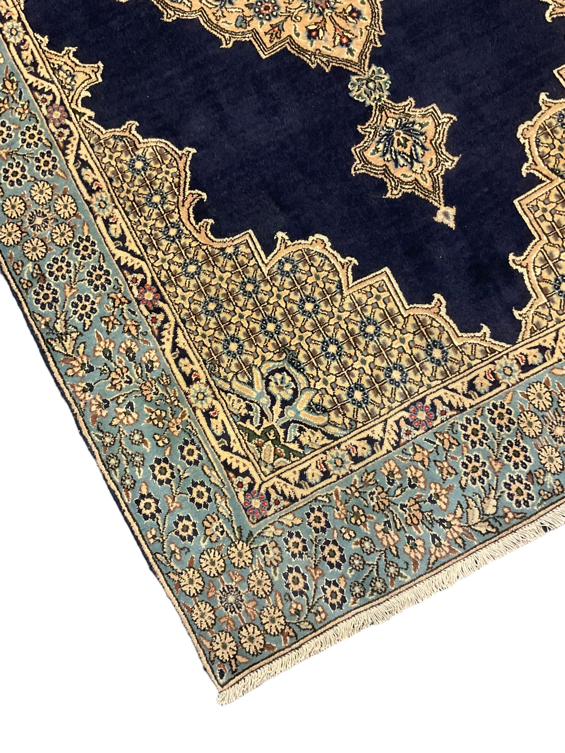 Central Persian Qum indigo ground rug with silk inlay, the plain field decorated with floral design medallion and lattice spandrels, the wide border decorated with trailing flowers and foliage 