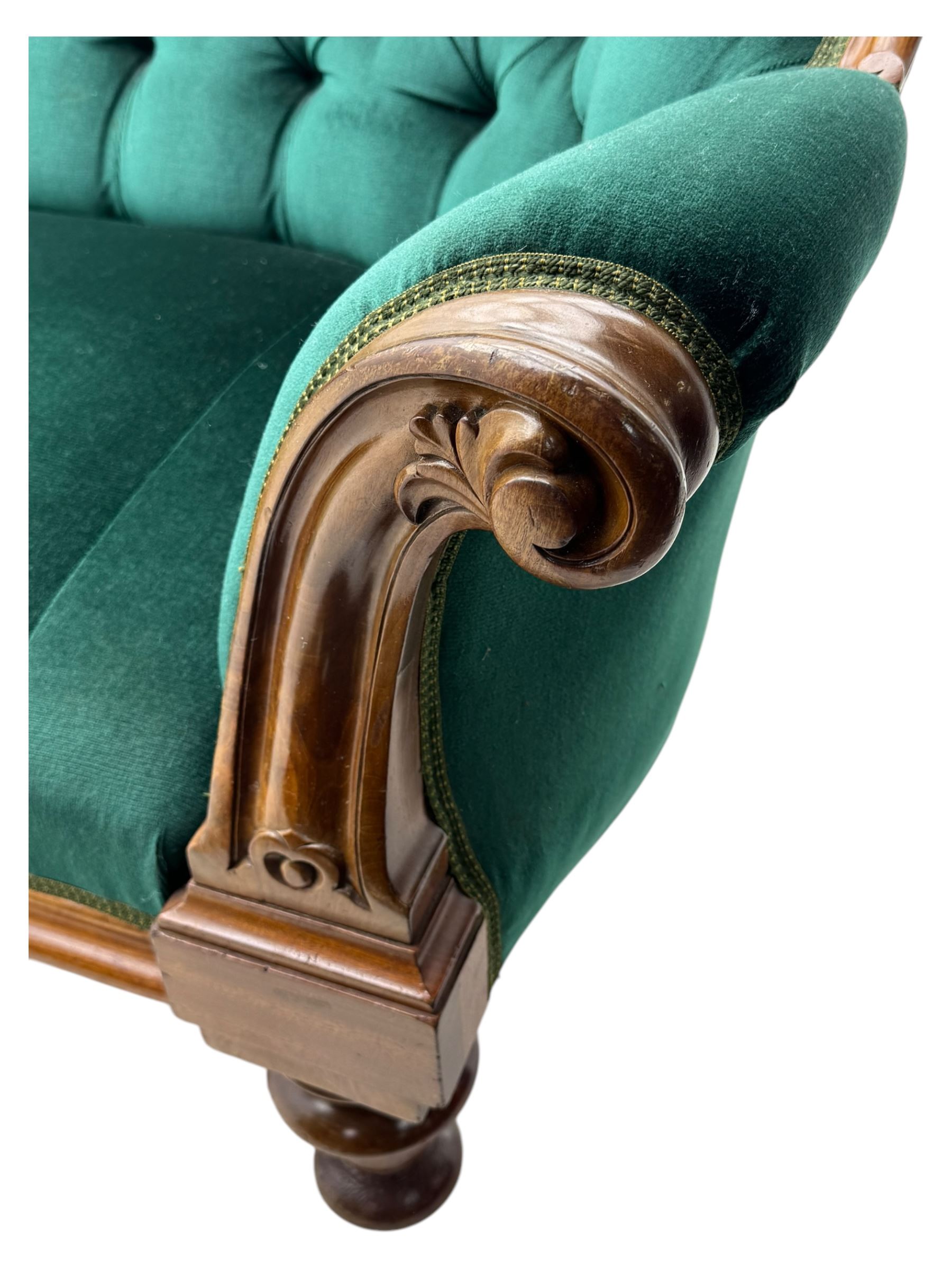 Victorian mahogany settee, upholstered in green buttoned fabric, moulded frame and scroll carved arm terminals, turned supports on castors