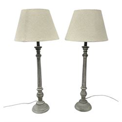 Pair of composite grey washed table lamps with a slender column upon a circular foot with natural linen shades
