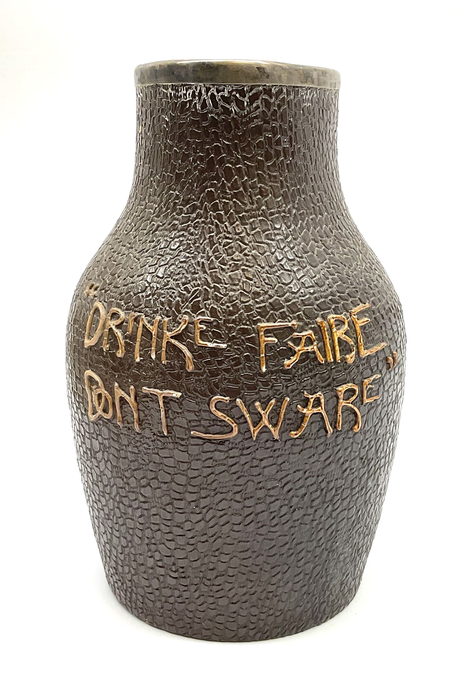 A Doulton Lambeth stoneware jug, with silver mounted collar, hallmarks rubbed, maker's mark probably Cornelius Desormeaux Saunders & James Francis Hollings (Frank) Shepherd, the leather effect body titled 'Drinke Faire Don't Sware', with impressed marks beneath including 'Manufactured for Sidney W Allen 39 White Rock Hastings', H18.5cm. 