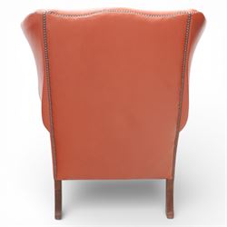 Georgian design red leather wingback armchair, with shaped back and scrolled arms, and close brass studded trim, upon cabriole front legs with claw and ball feet
