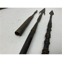 Native hand forged iron fishing spear, the V-shaped head with barbed neck and hewn haft L171cm; and two other hand forged iron spear heads, one with remains of copper bound haft (3)