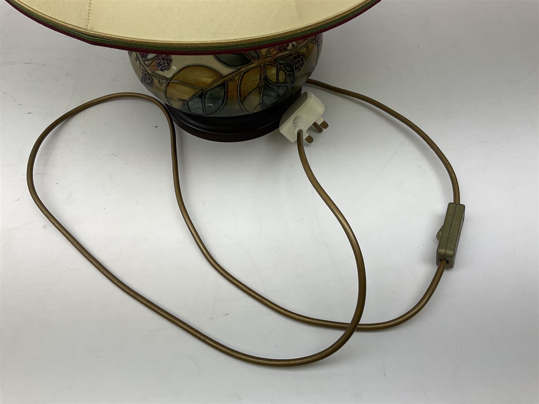 Moorcroft table lamp of squat baluster form, decorated in the Autumn Blackberry, with Moorcroft cream fabric shade with gold, green and red piping, overall H38cm
