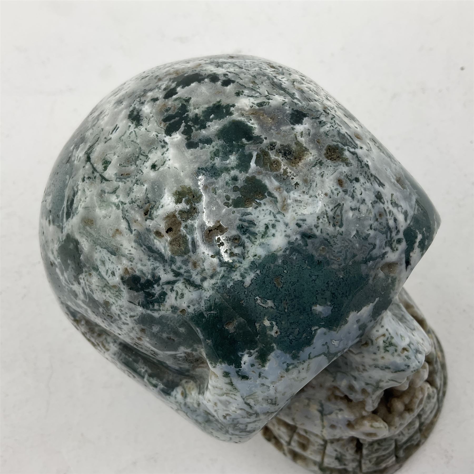Carving of a skull in moss agate, H9cm, L12cm 