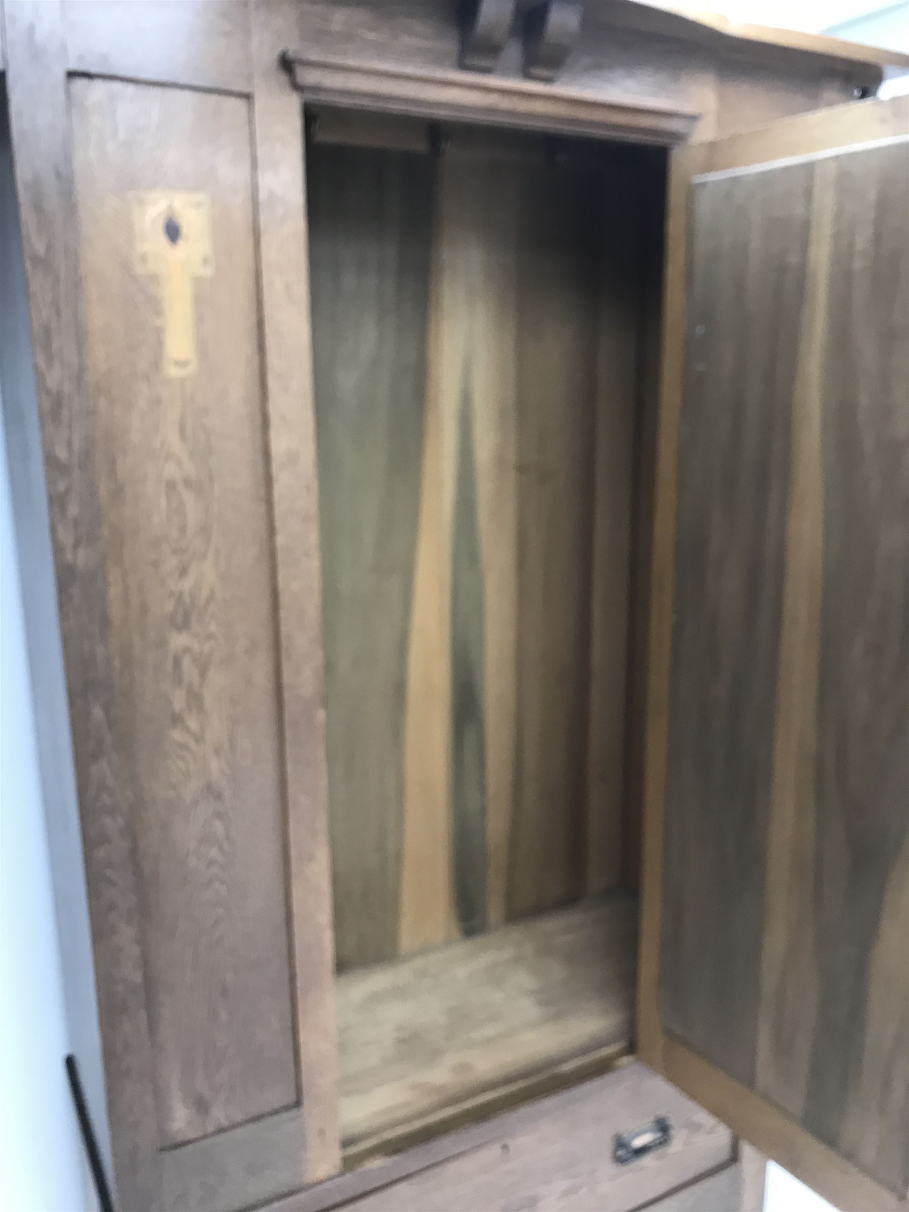 Arts and Crafts period oak wardrobe, projecting shaped cornice, single bevel edged mirrored door above drawer