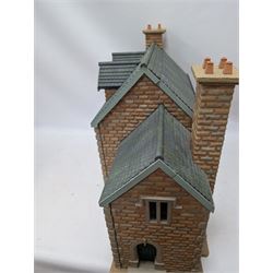 1:24 scale stone effect three-storey cottage dolls house, with green arched door and lattice effect windows, decorated to the interior with wooden floors, wired lighting and fire places, H45cm, W57cm, D26cm