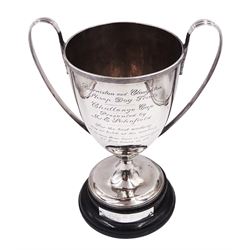 George III silver trophy cup, with reed border to rim and twin handles with acanthus leaf mounts, upon knopped stem and stepped circular foot, each with reed detailing, the body with presentation engraving 'Burniston and Cloughton Sheep Dog Trials Challenge Cup, presented by Mr E Schofield, for the best working dog or bitch at the meeting, to be won three times in succession or five times in all', with former winners engraved verso, hallmarked Henry Chawner, London 1788, upon ebonised wooden base with engraved winners plaque,  including plinth and handles H31.8cm
