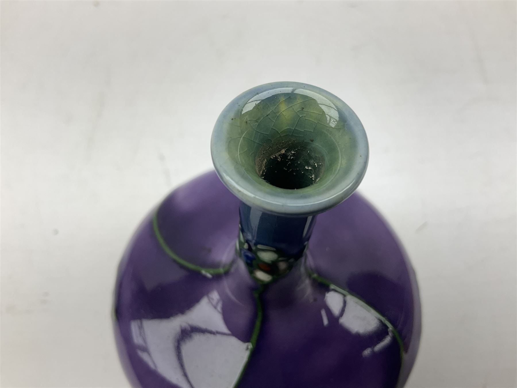 Three Minton Secessionist vases, with tube-lined stylised flower decoration, two upon a red ground and third upon a purple ground, all with printed mark to base 'Minton Ltd, No. 33', H13cm