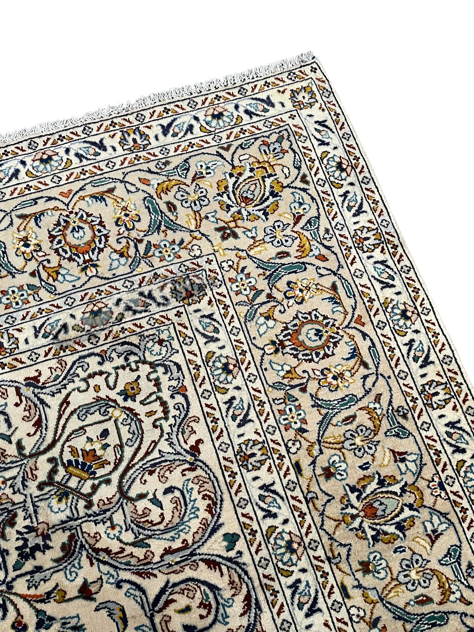 Persian Kashan ivory ground carpet, central pole medallion surrounded by swirling leafy branches and stylised plant motifs, scrolled foliate spandrels, the main border decorated with scrolling pattern and repeating palmettes, within floral patter guard stripes 