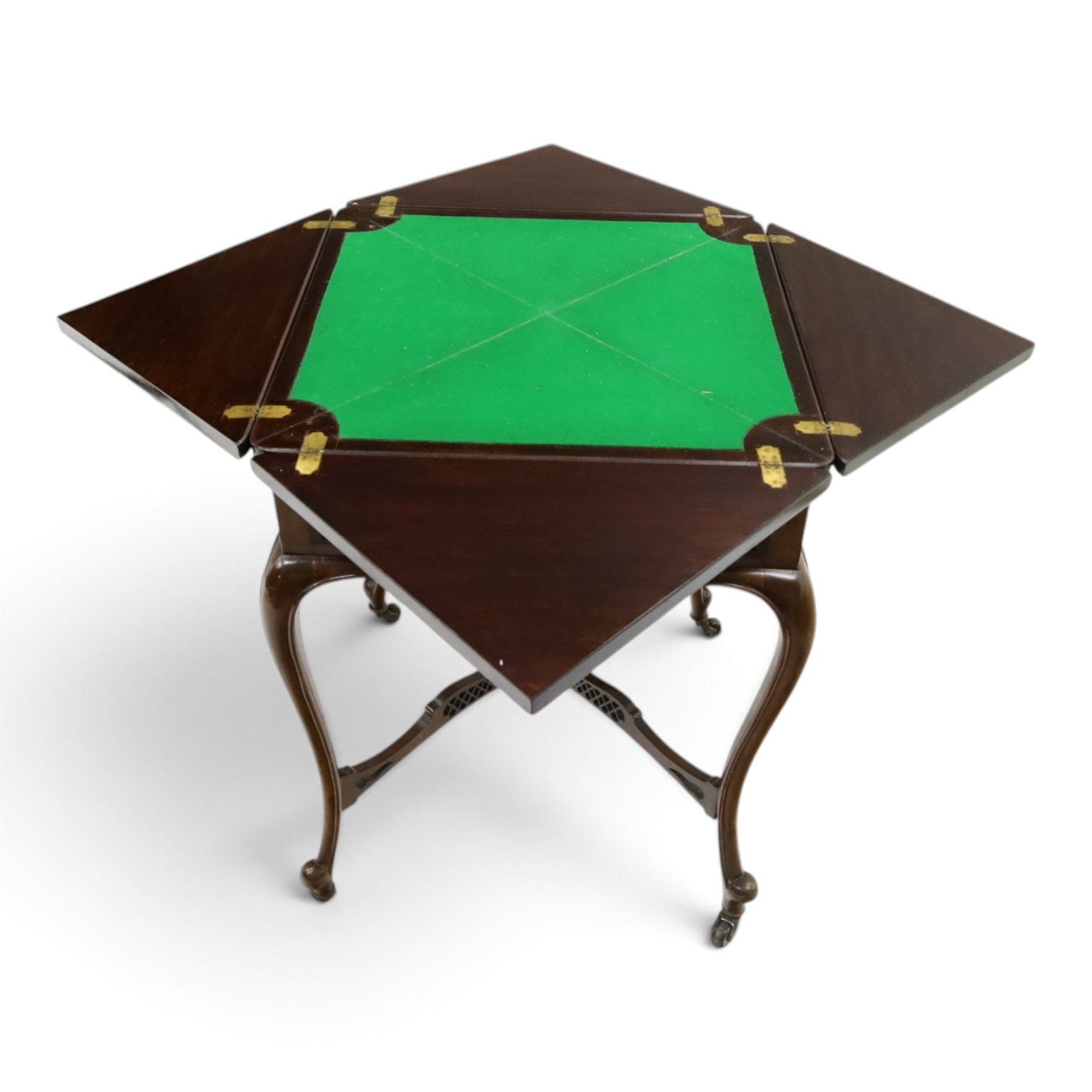 Edwardian carved mahogany envelope card table, the rectangular quadruple hinged top enclosing baize-lined interior, the single frieze drawer and sides with blind-fretwork carving, over cabriole supports with scroll feet and castors united by pierced lattice fretwork X-stretcher with turned finial