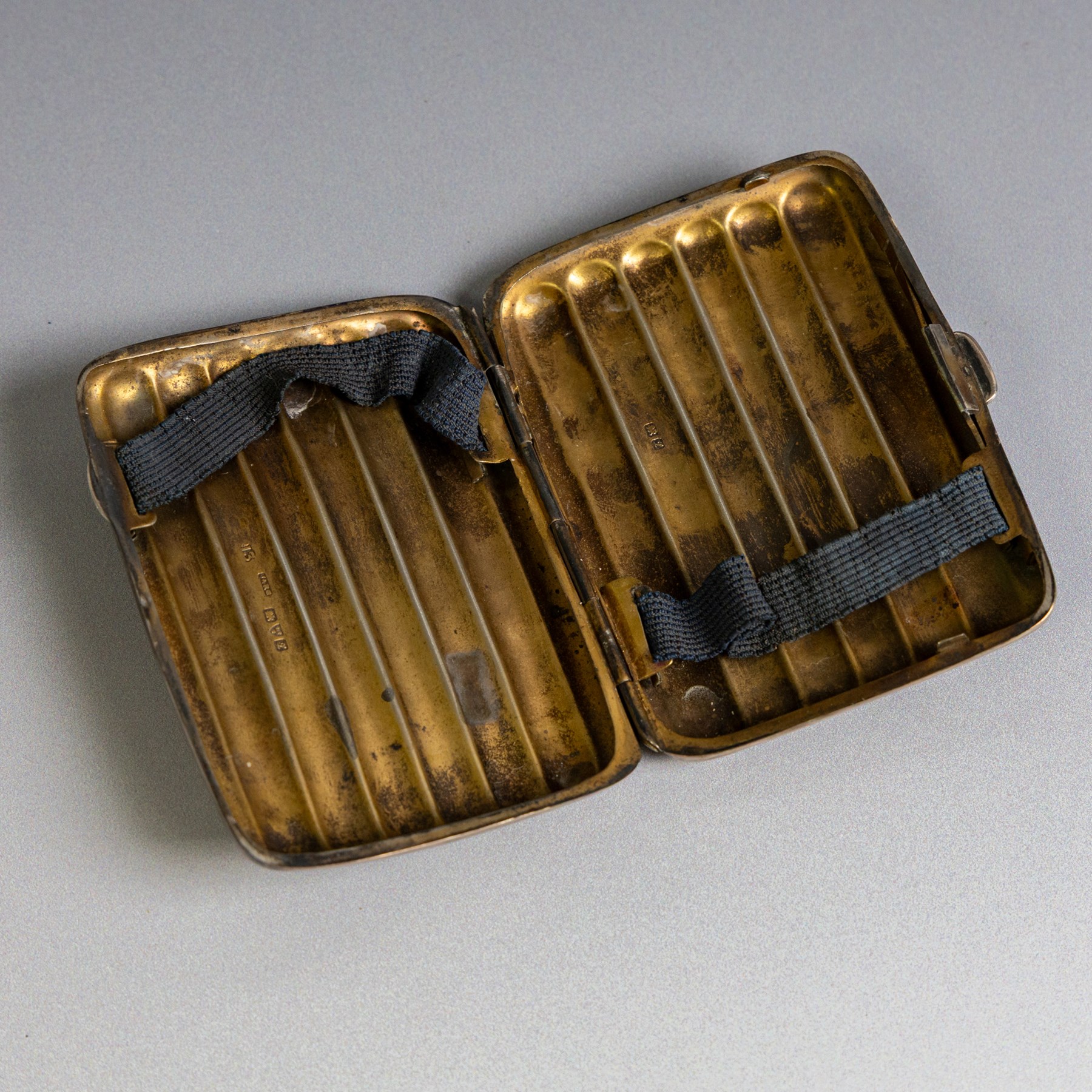 Two early 20th century silver cigarette cases, comprising a rectangular example with foliate decoration and vacant shield cartouche and a 1920s example with engine turned decoration and engraved initials, both hallmarked