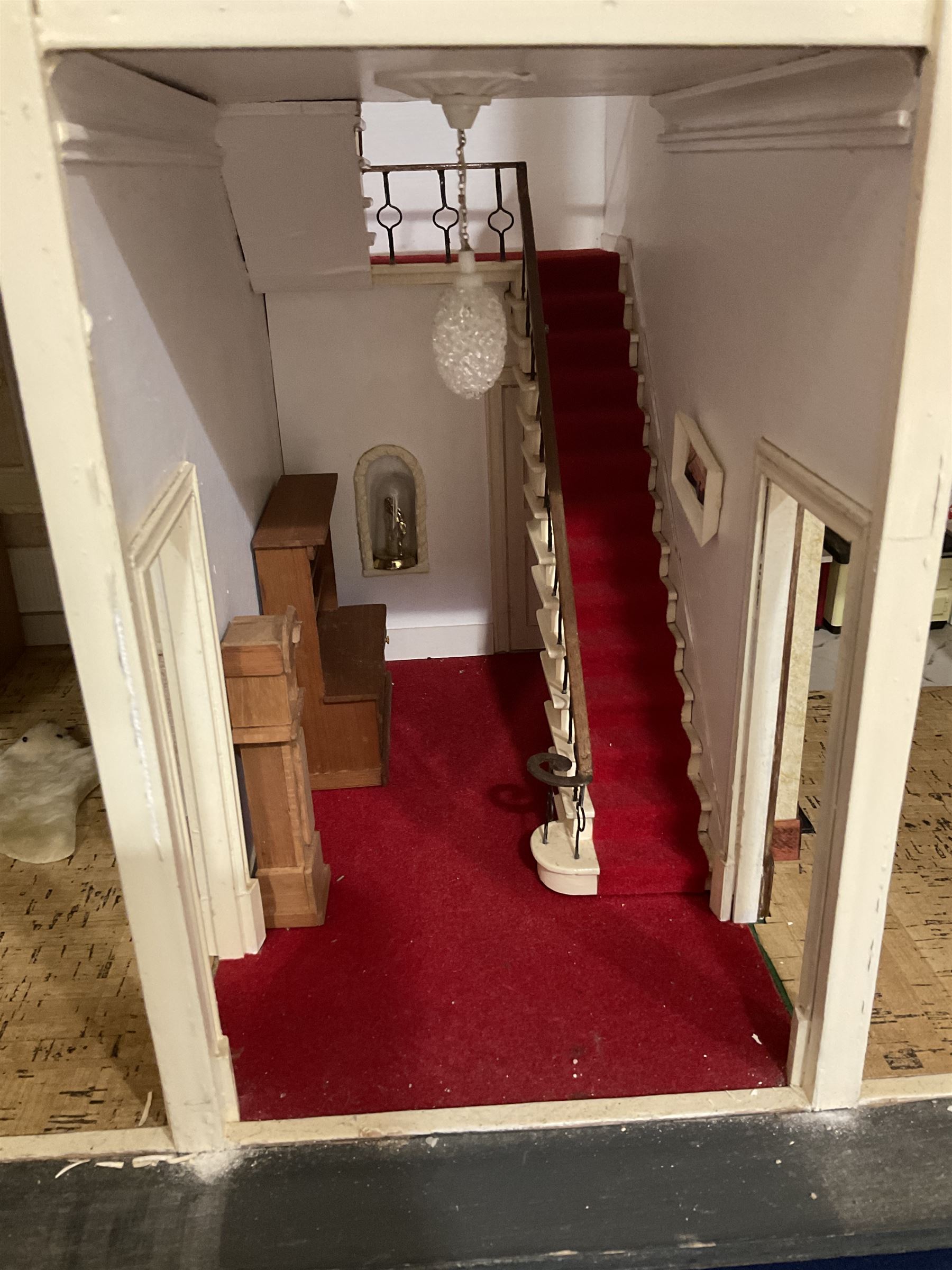 Kit-built wooden dolls house, possibly by Honeychurch, as a 19th century style double fronted two-storey residence; with stucco walls and flat roof with circular skylight and parapet with balusters; central door with fanlight, Corinthium columns and balcony over; simulated sash windows to three sides; hinged front facade opening to reveal a partially furnished interior with central hall, stairs and landing, two ground floor rooms and two first floor en suite bedrooms; wired for electric lighting W69cm H70cm D41cm