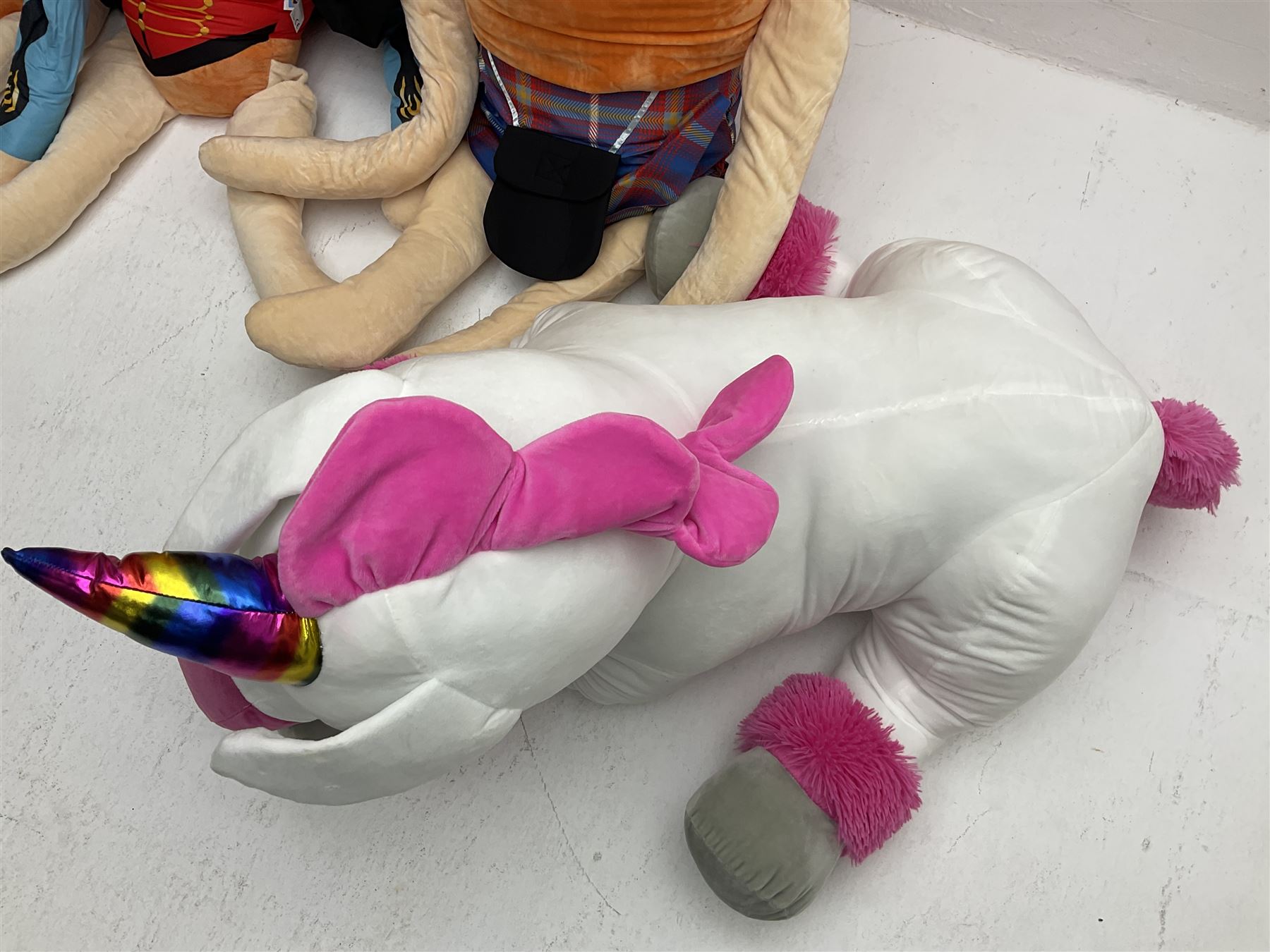 Three large ALDI Kevin carrots and giant unicorn stuffed toy together with quantity of smaller carrots