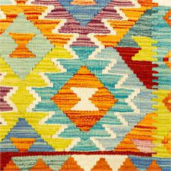 Afghan Chobi kilim flatweave runner with a repeating stepped diamond medallion design in live green, rust, teal, purple, and ivory, framed by chevron and geometric borders