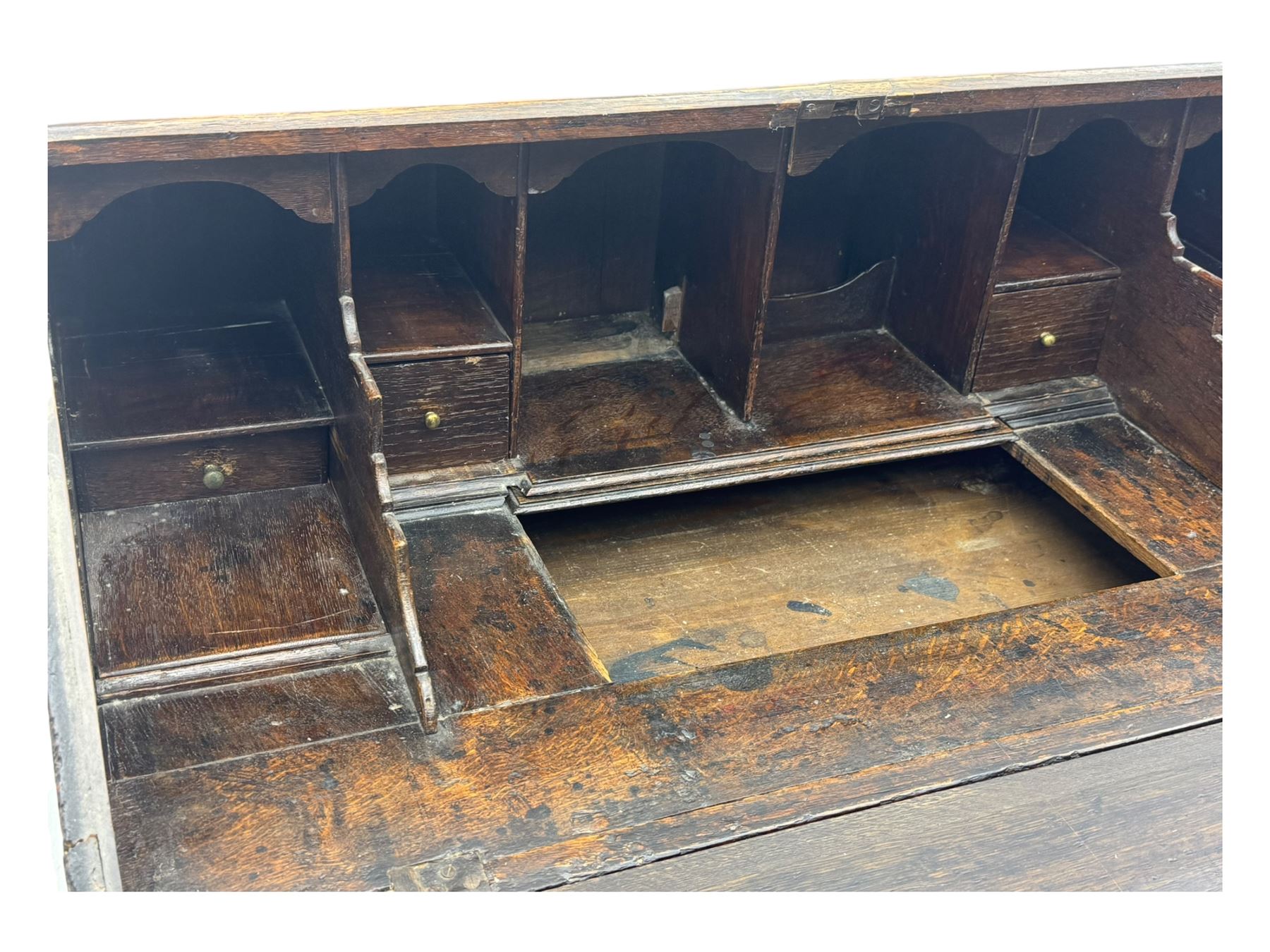 George III oak bureau, sloped fall-front enclosing a fitted interior with pigeonholes, small drawers, and a central compartment, over two short and two long drawers, brass escutcheons and drop handles, raised on bun feet