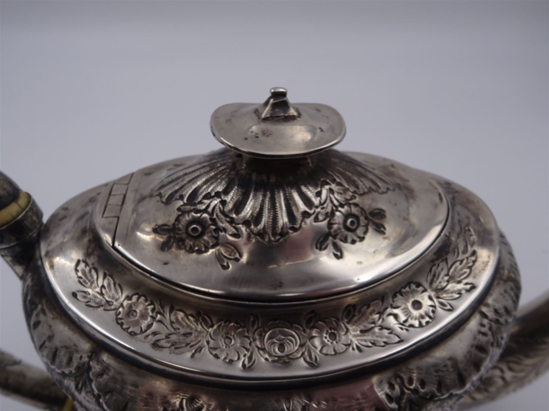 George III silver teapot, of oval form, with embossed foliate, floral and scroll decoration and engraved central cartouche, with acanthus capped C handle with ivory insulators, hallmarked John Emes, London 1807 This item has been registered for sale under Section 10 of the APHA Ivory Act
