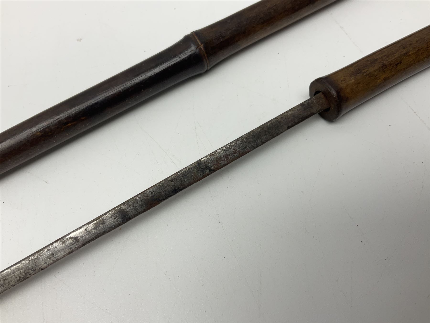 Early 20th century bamboo sword stick with 39cm oblong section blade L85cm overall; and two malacca cane swagger sticks, one with white metal mounts the other with yellow metal mounts (3)