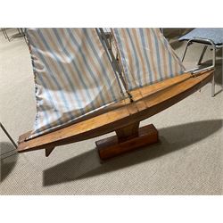Large pond yacht with simulated planked mahogany deck, mahogany hull, wooden keel and stern fin and tubular aluminium mast with two sails; on wooden stand L131cm H on stand 177cm