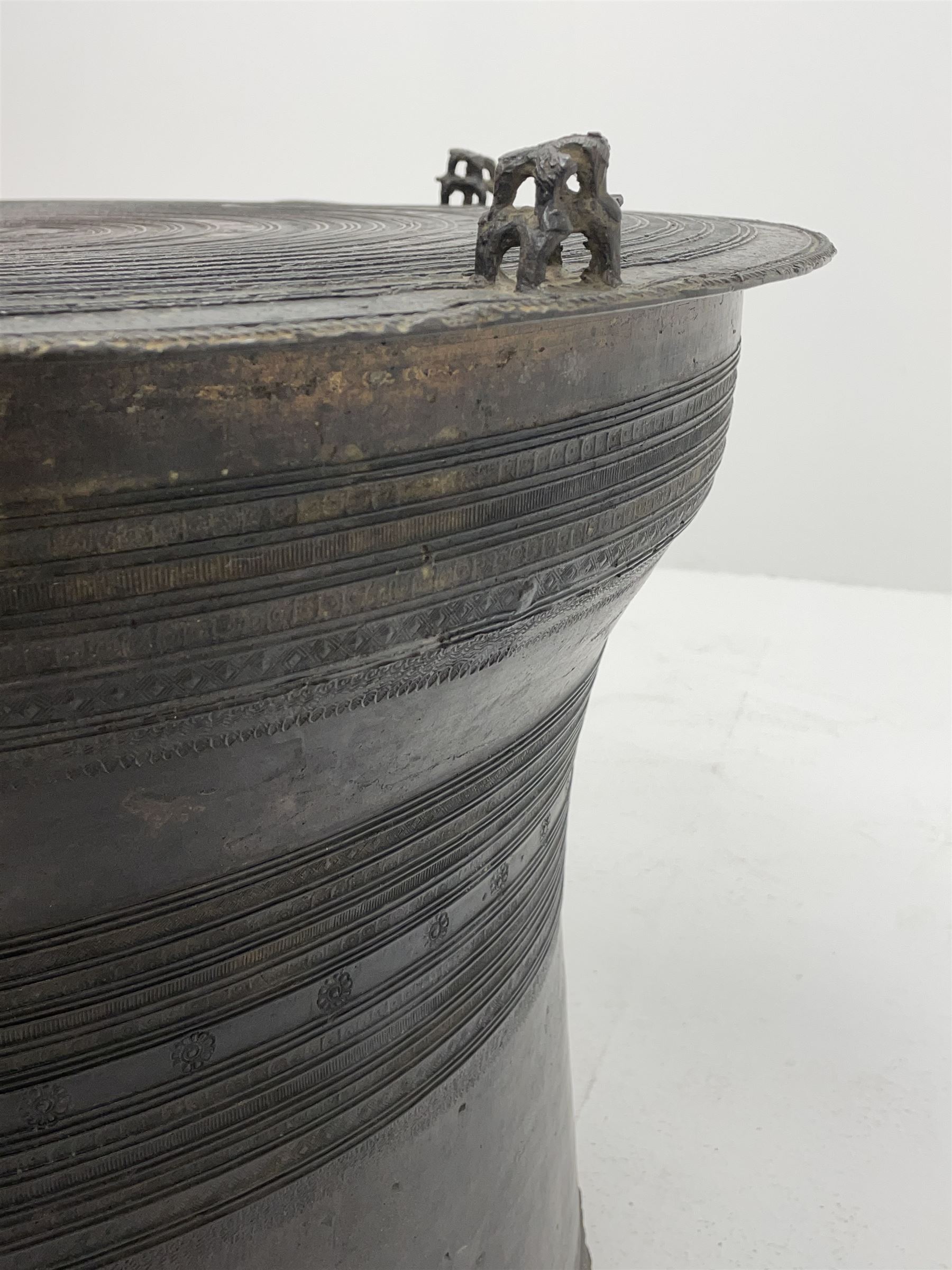 Dong Son style Southeast Asian bronze rain drum, the top decorated with concentric bands with stylised motifs and geometric shapes, central twelve point star, the tapered body with loop handles, set with small elephant and animal figures