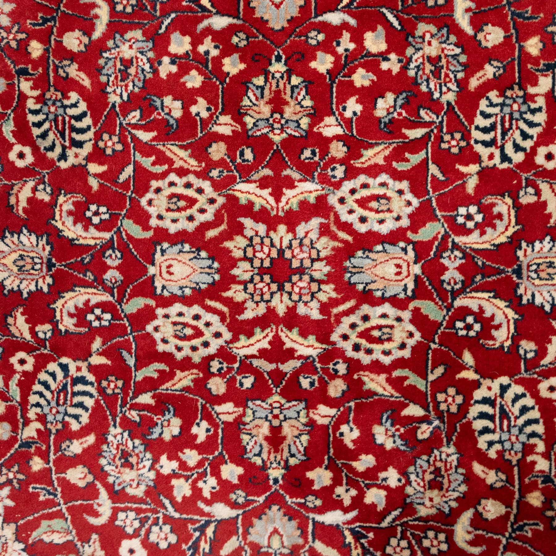 Persian crimson ground rug, interlacing floral stems linking ivory palmettes, rosettes and serrated leaves, within a navy floral border flanked by ivory patterned guards