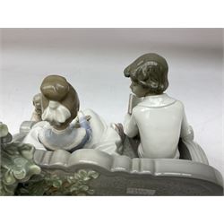 Lladro figure, Poetry of Love, modelled as a boy seated reading from a book next to a girl on garden bench with a dog at her feet, sculpted by Regino Torrijos, with original box, no 5442, year issued 1987, year retired 1998, H22cm