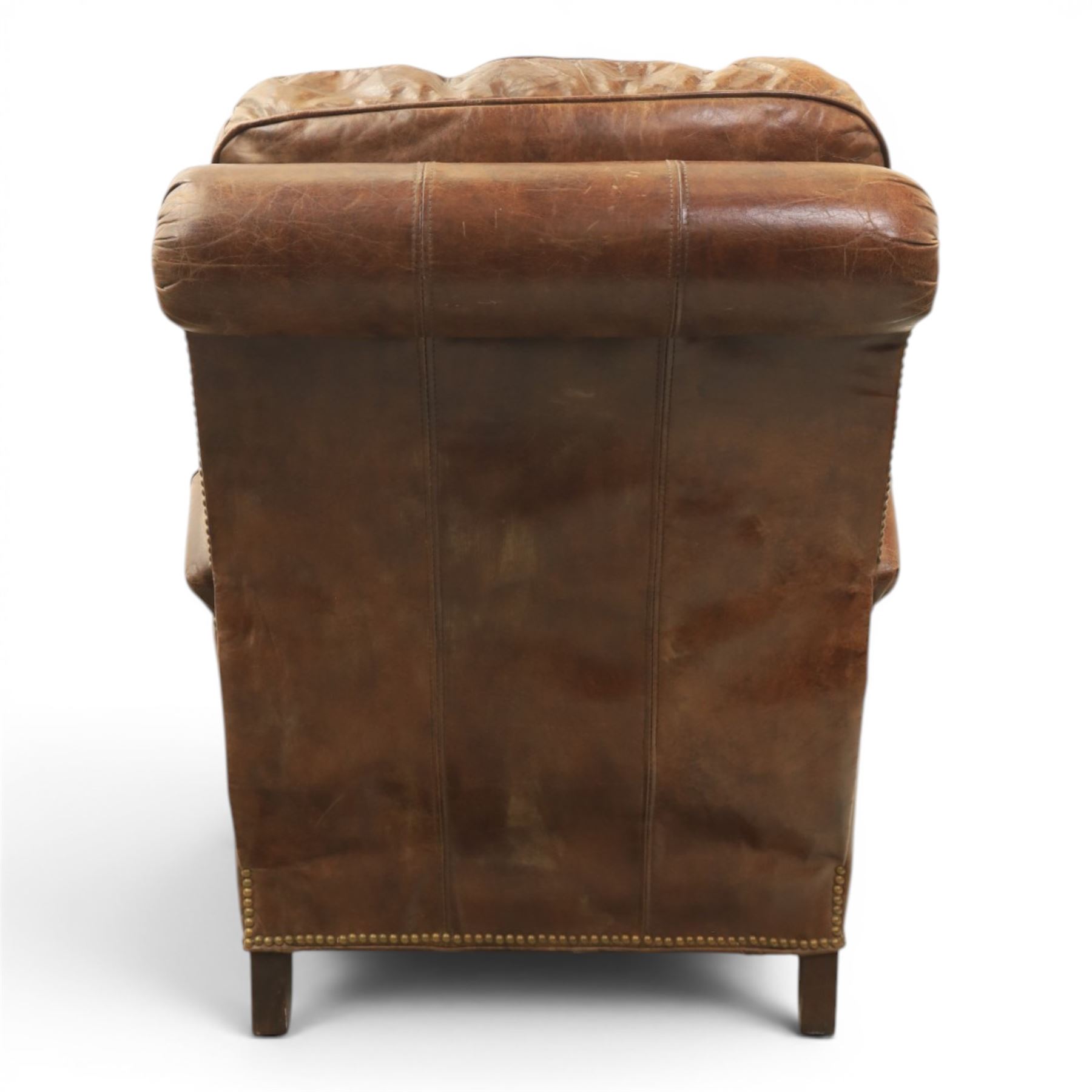 Art Deco style brown leather reclining armchair, scrolled arms with brass studded trim, reclining foot rest and back, fixed back and loose seat cushion,
