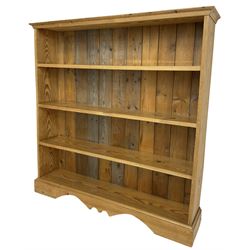 20th century pitch pine open bookcase, fitted with three shelves, on bracket feet with shaped apron