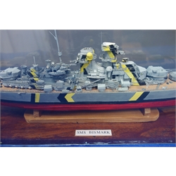  Scale built model of SMS Bismarck, wooden hull with plastic superstructure, guns and equipment, on stand in perspex display case with label 'Model built by Don Micklethwaite 2013', signed, L81cm, H23cm, D16cm  