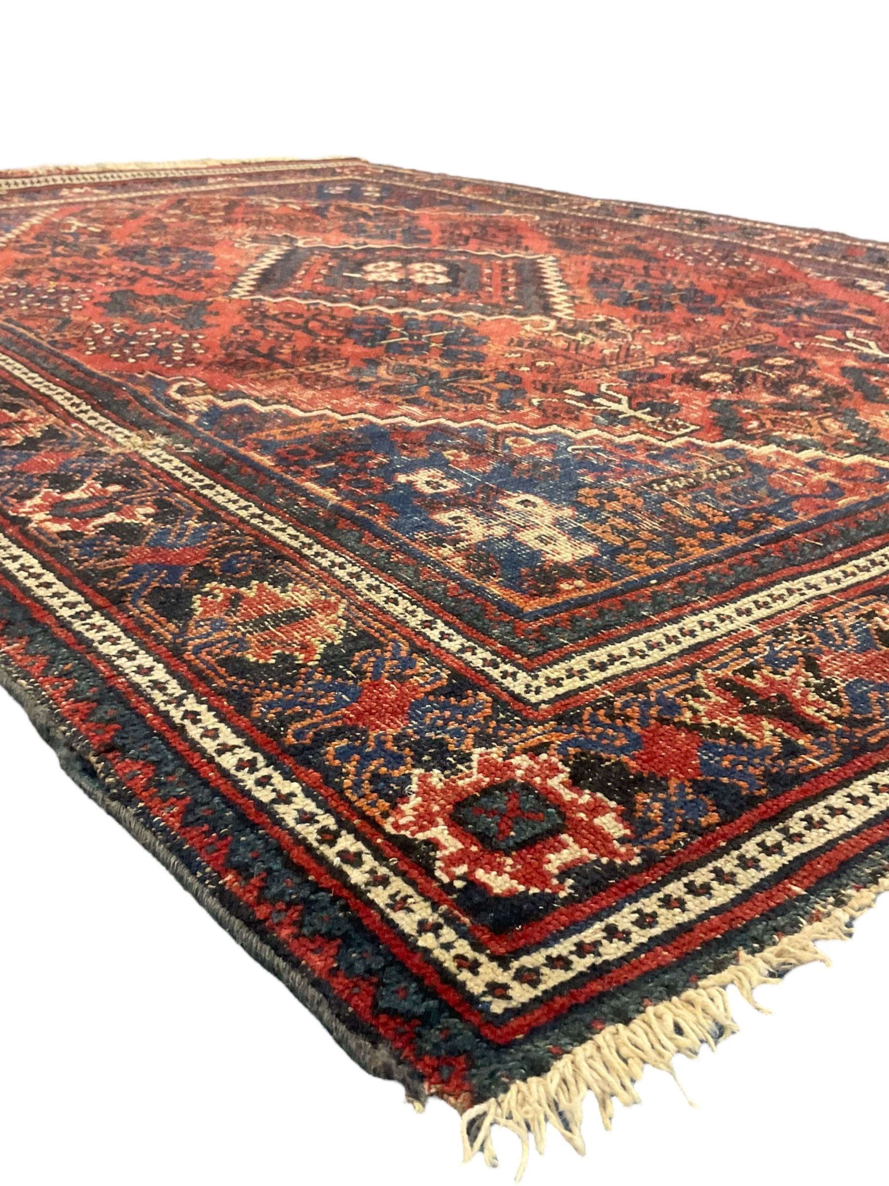Persian Hamadan red ground rug, the field decorated with floral motifs with central lozenge medallion, guarded border decorated with repeating stylised plant motifs