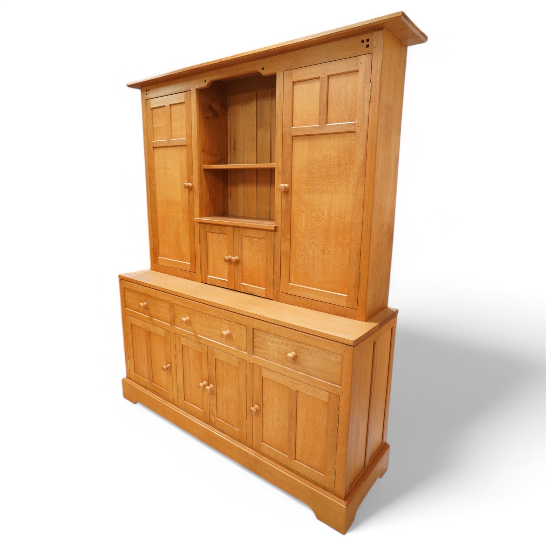 Yorkshire oak dresser, projecting top over open centre fitted with shelf, small double cupboard and flanking full height cupboards, the lower section fitted with three drawers and cupboards, enclosed by panelled doors, on plinth base
