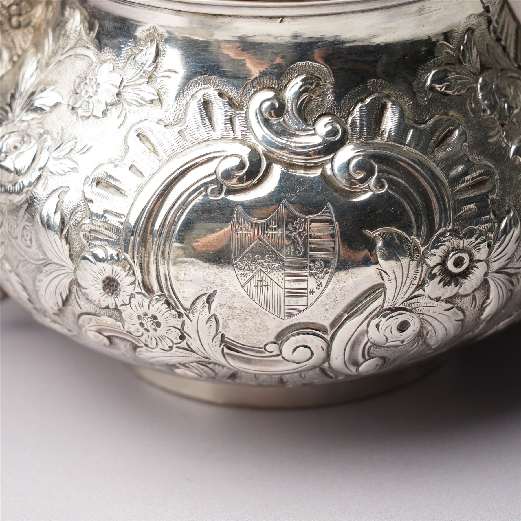 Matched three piece silver tea set comprising teapot of squat circular form London 1827,  milk jug of similar date and sugar bowl with Britannia standard marks, all with later embossed floral decoration and coat of arms, all marks rubbed
