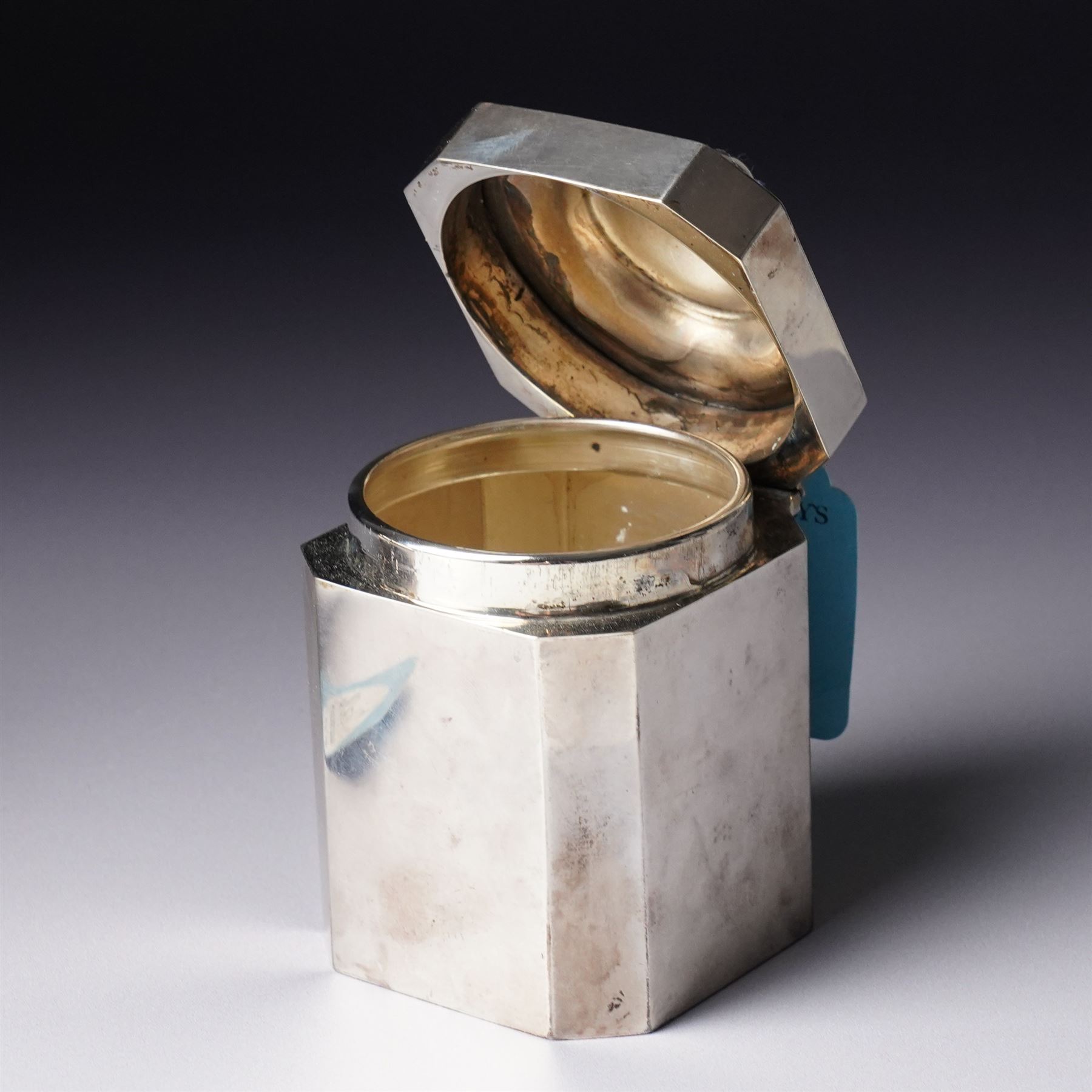 Silver square tea caddy with hinged lid and canted corners H9cm Birmingham 1912 Maker Synyer & Beddoes and a silver cream jug with crimped rim and scroll handle engraved with a crest  London 1901 Maker William Hutton & Sons