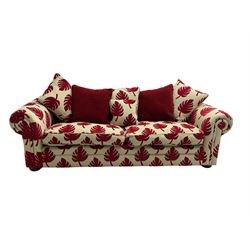 Large three seat sofa, upholstered in cream and red leaf patterned fabric with matching scatter cushions, raised on carved compressed bun feet