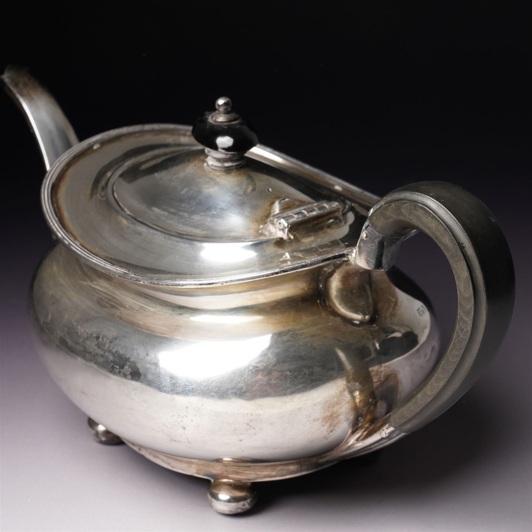 Silver tea pot of oval form with ebonised handle and lift on compressed bun feet Sheffield 1919 Maker Atkin Bros.