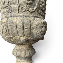 Pair of George III design antiqued composite stone garden urns of campana form, the egg-and-dart everted rim over a waisted body relief moulded with scrolling fruiting foliage and flowerheads, the gadrooned underbelly with twin mask ornaments, the knopped stems on fluted socles, raised on faux panelled square pedestal bases