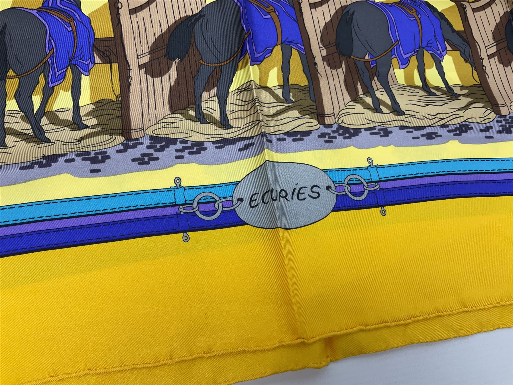 Hermès 'Ecuries' silk scarf, designed by Hugo Grygkar in 1947, printed with twenty horses in their respective stables, on yellow ground contained within stitched effect blue and purple and darker yellow gold borders, with rolled hand stitched edges and Hermes material label, 87cm square