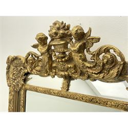Large Victorian style gilt cushion framed mirror, putti holding urn with scrolled foliage pediment above central rectangular bevelled plate, the frame decorated with moulded foliate, each corner set with ornate cartouche